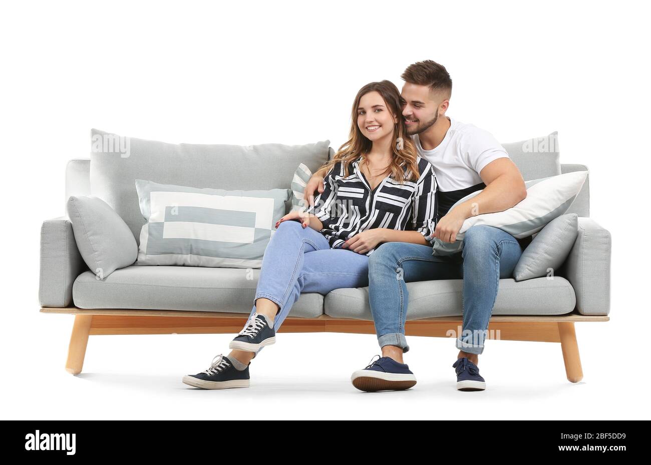 Young couple sitting on sofa against white background Stock Photo - Alamy