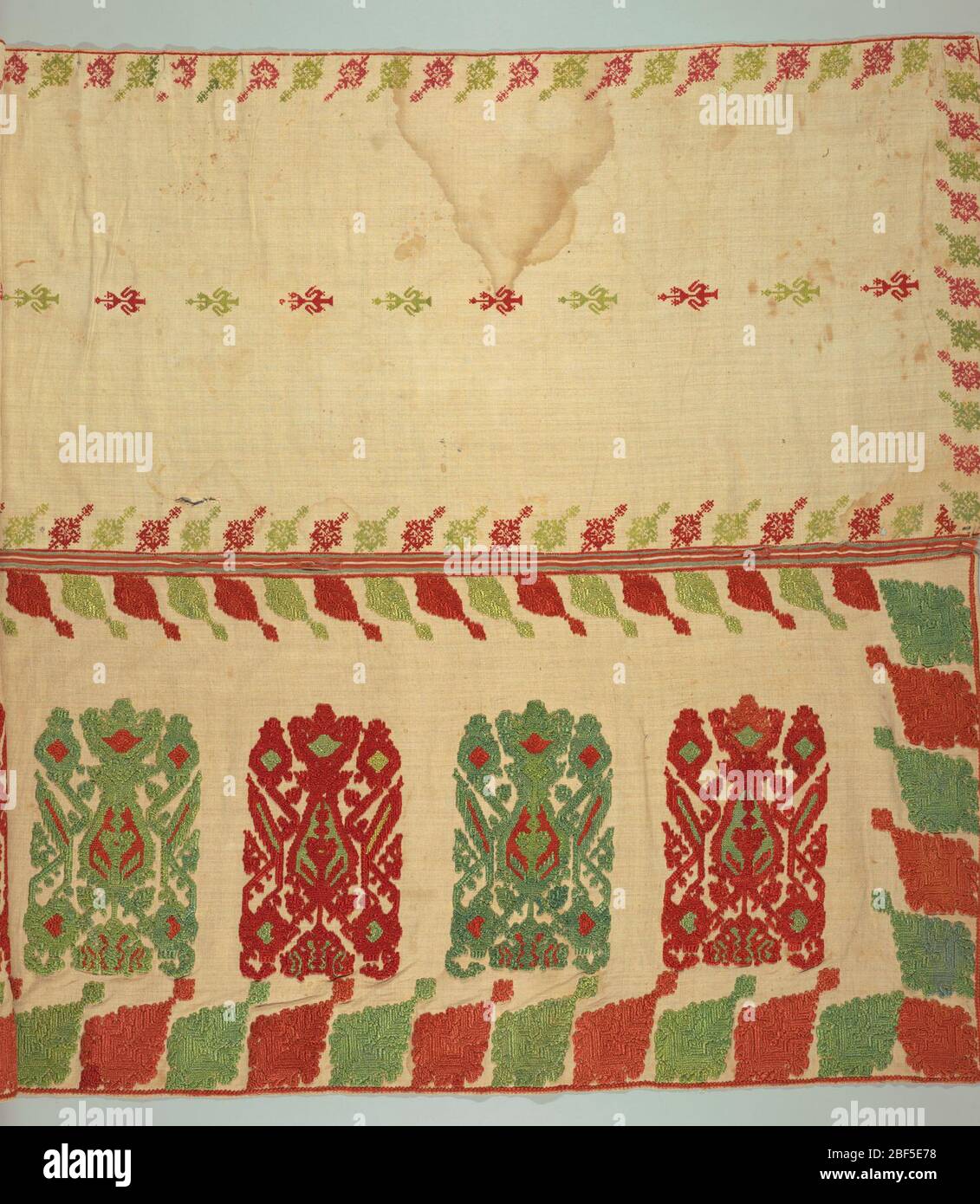 Valence. Two widths of linen sewn to a red and green striped silk ribbon, embroidered in red and green silk cross stitch. Lower width: large units of Glastra pattern in a row, set vertically, border of oblique leaves on all four sides. Stock Photo