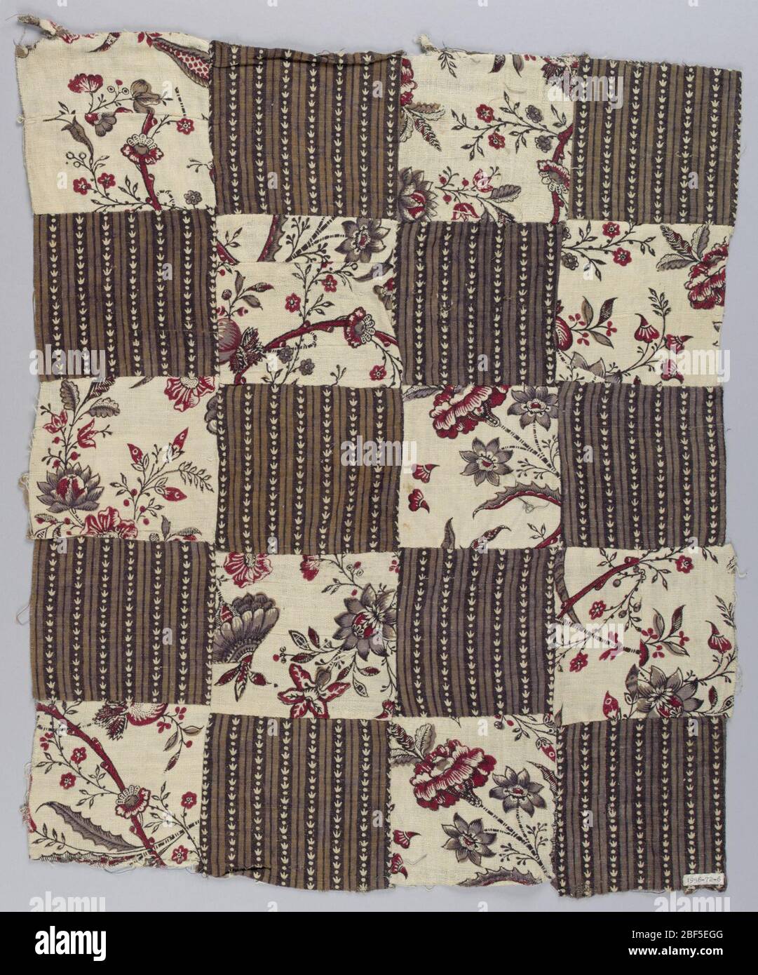 Patchwork. Piece of patchwork consisting of alternating patches made from two different fabrics, about 4 inches square. One fabric has flowers in red, dark brown and violet with black outlines for stems on a white ground. Stock Photo