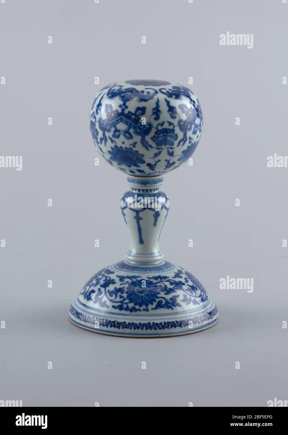 Wig stand. Bulbous wig stand on a baluster stem and wide, hemispherical base. Stem painted with hanging tassels. Stock Photo