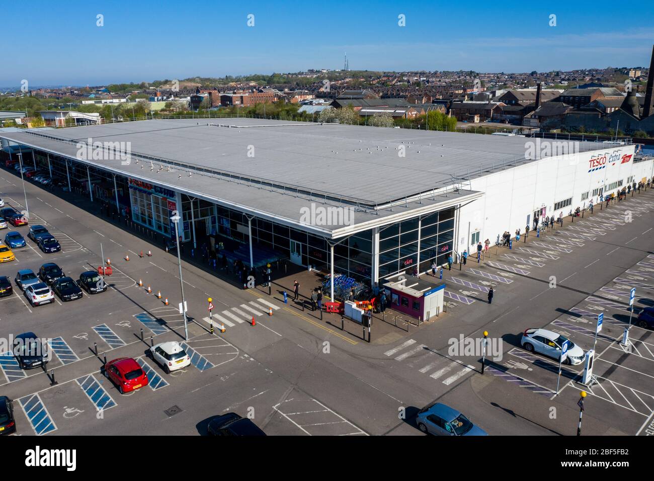 People queue 2 metres apart for a long distance outside of the Tesco extra store in Longton, Stoke on Trent, Social distancing, Covid 19, Coronavirus Stock Photo