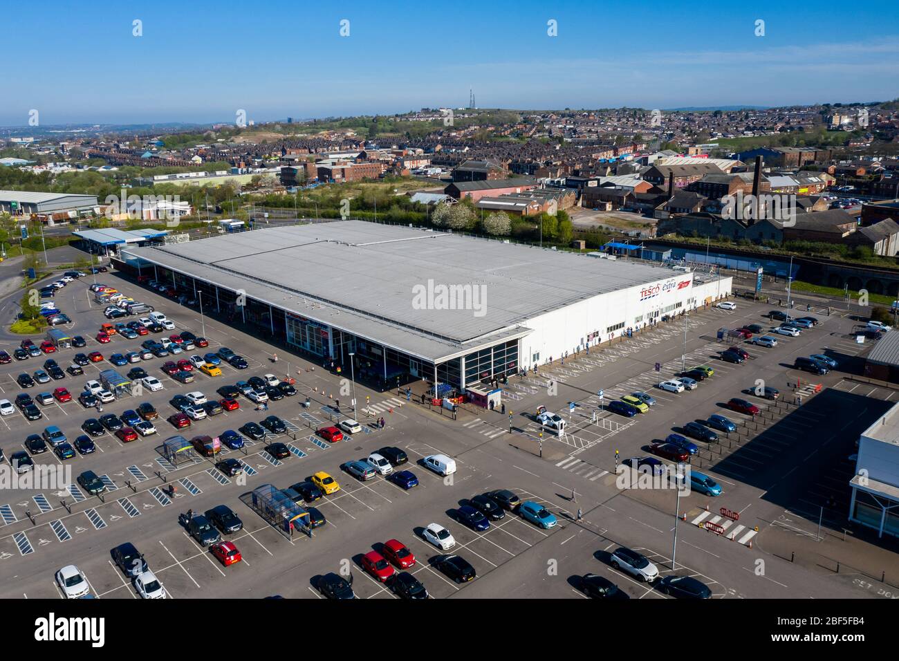 People queue 2 metres apart for a long distance outside of the Tesco extra store in Longton, Stoke on Trent, Social distancing, Covid 19, Coronavirus Stock Photo