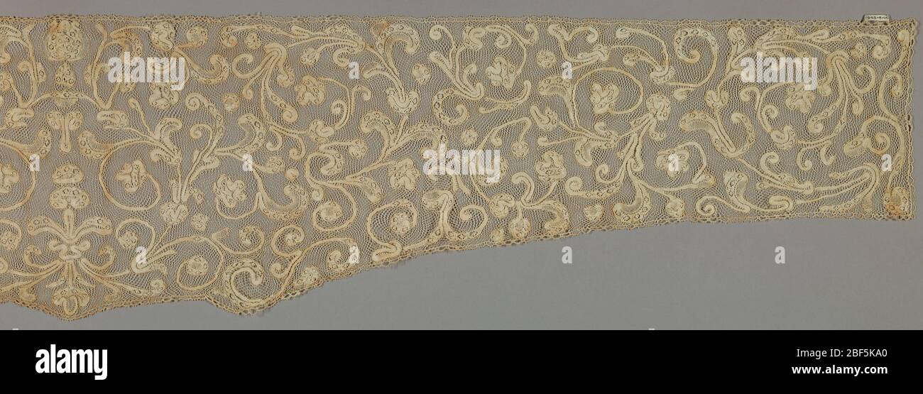 Sleeve ruffle. Design of scrolling stems with leaves and flowers, running to the right and left from central ornament. Ground is of vrai droachel worked in several directions. Stock Photo