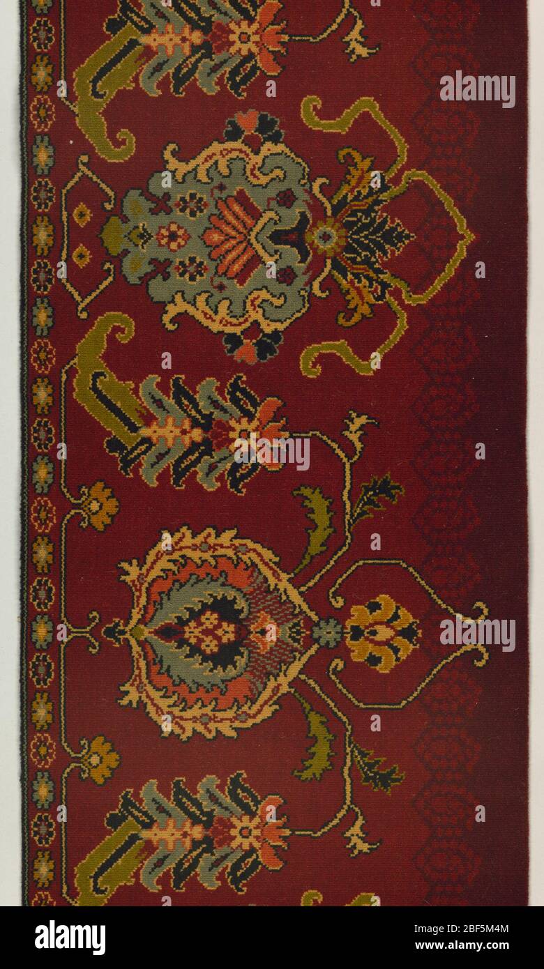 Carpet fragment. Floral rug design showing Persian influence in bold colors on a dark red ground. Wide plain weave selvage on left side. Stock Photo