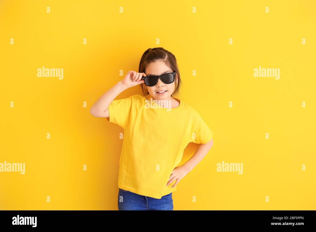 Funny little girl with sunglasses on color background Stock Photo Alamy