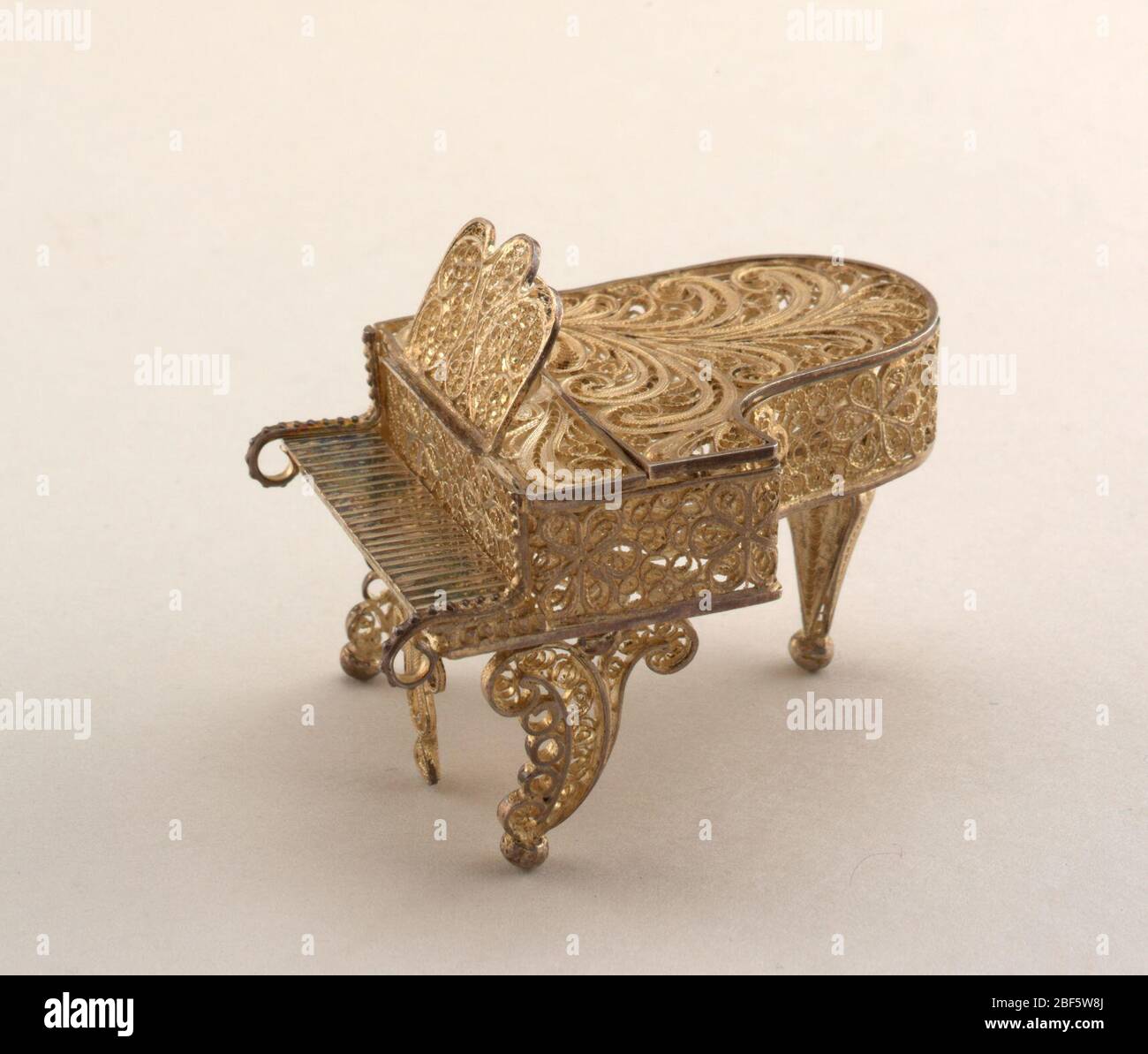 piano. Grand piano. Lid can be raised. Scrolled front legs, baluster rear leg. All-over decoration on case and rack of scrolled and rosetted filigree. Stock Photo