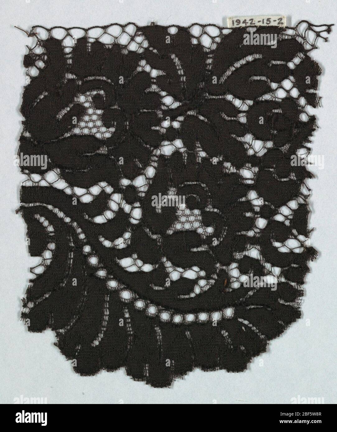 Fragment. Black Spanish blonde guipure lace; pattern of flowers and leaves and no ground. Stock Photo