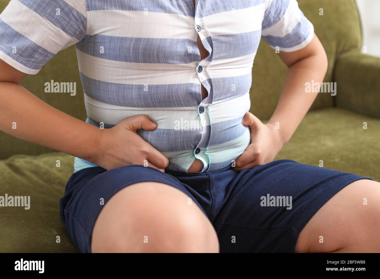 Overweight boy in tight clothes at home Stock Photo