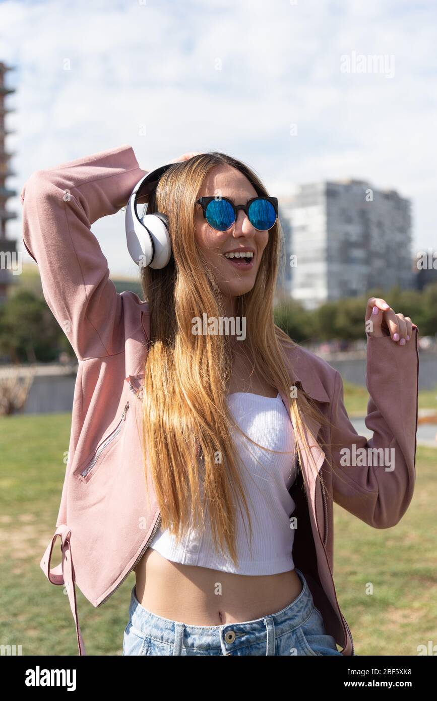 Young caucasian girl enjoys listening to music in a park in the city. Stock Photo