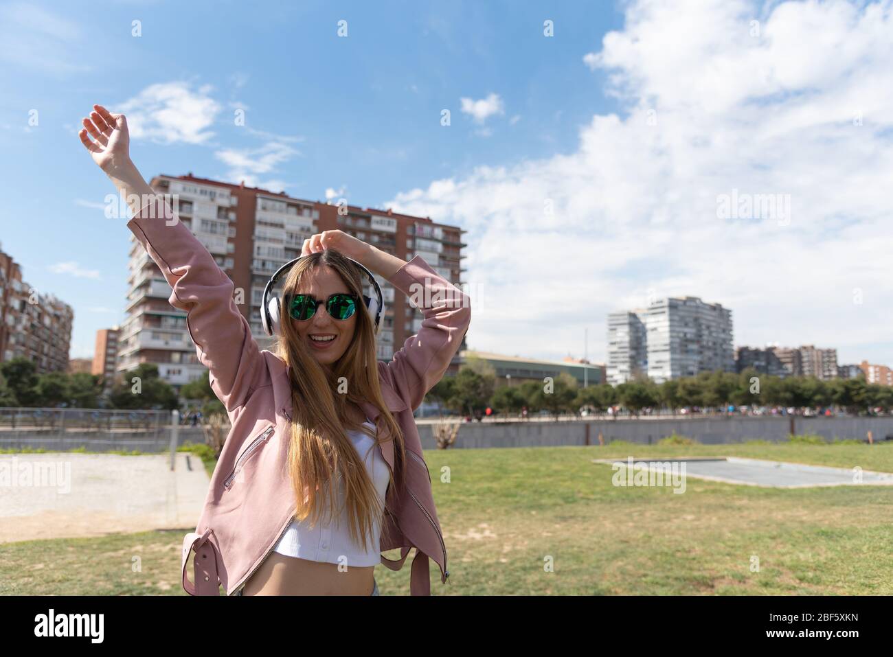 Young caucasian girl enjoys listening to music in a park in the city. Stock Photo