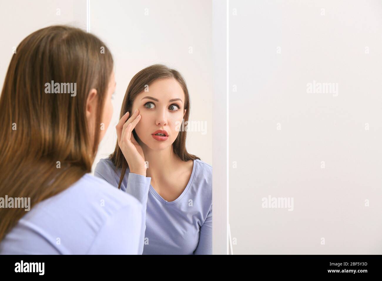Shocked young woman looking in mirror at home Stock Photo Alamy