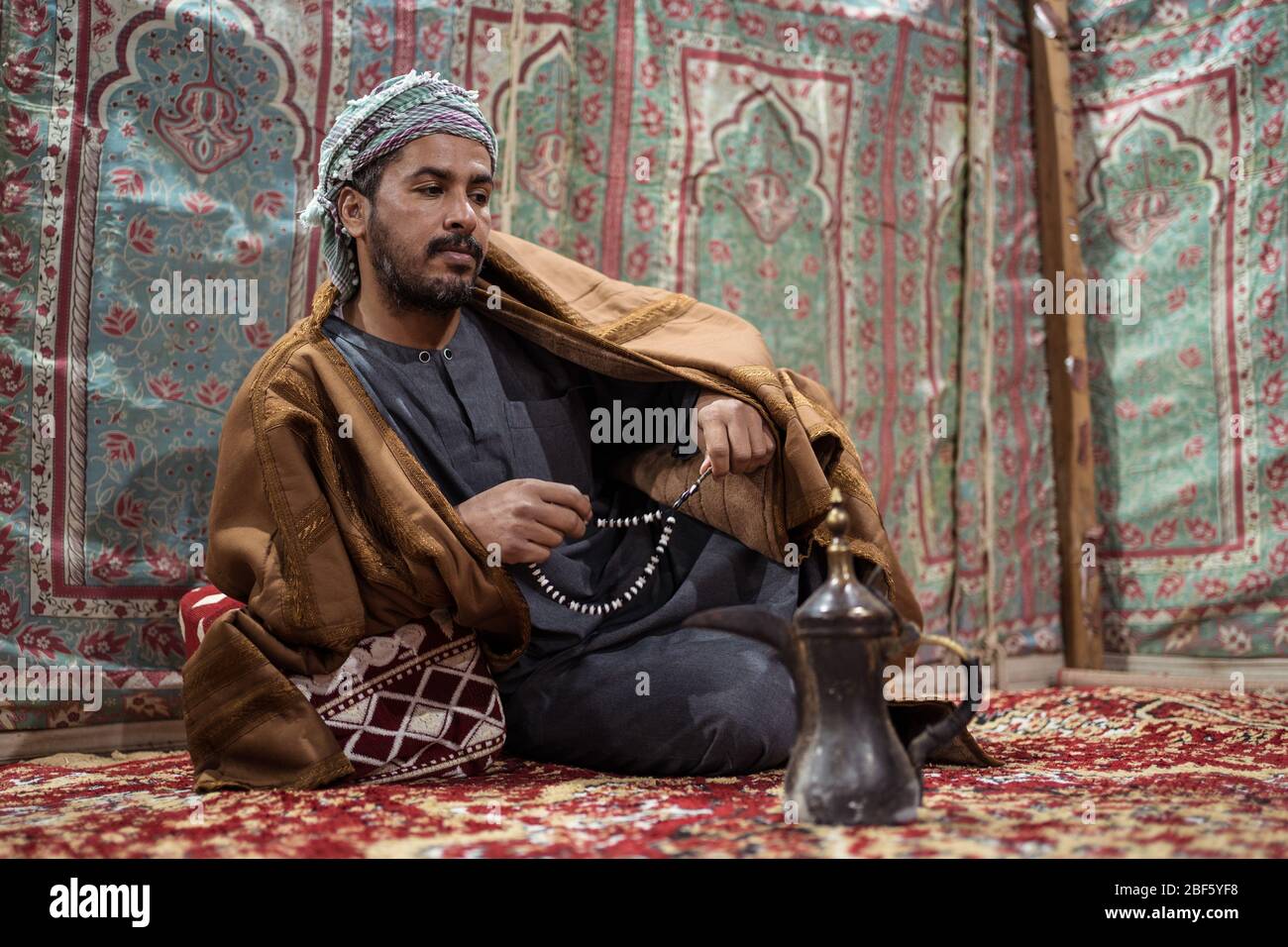 Bedouin man wearing traditional clothes praying with a tasbih while