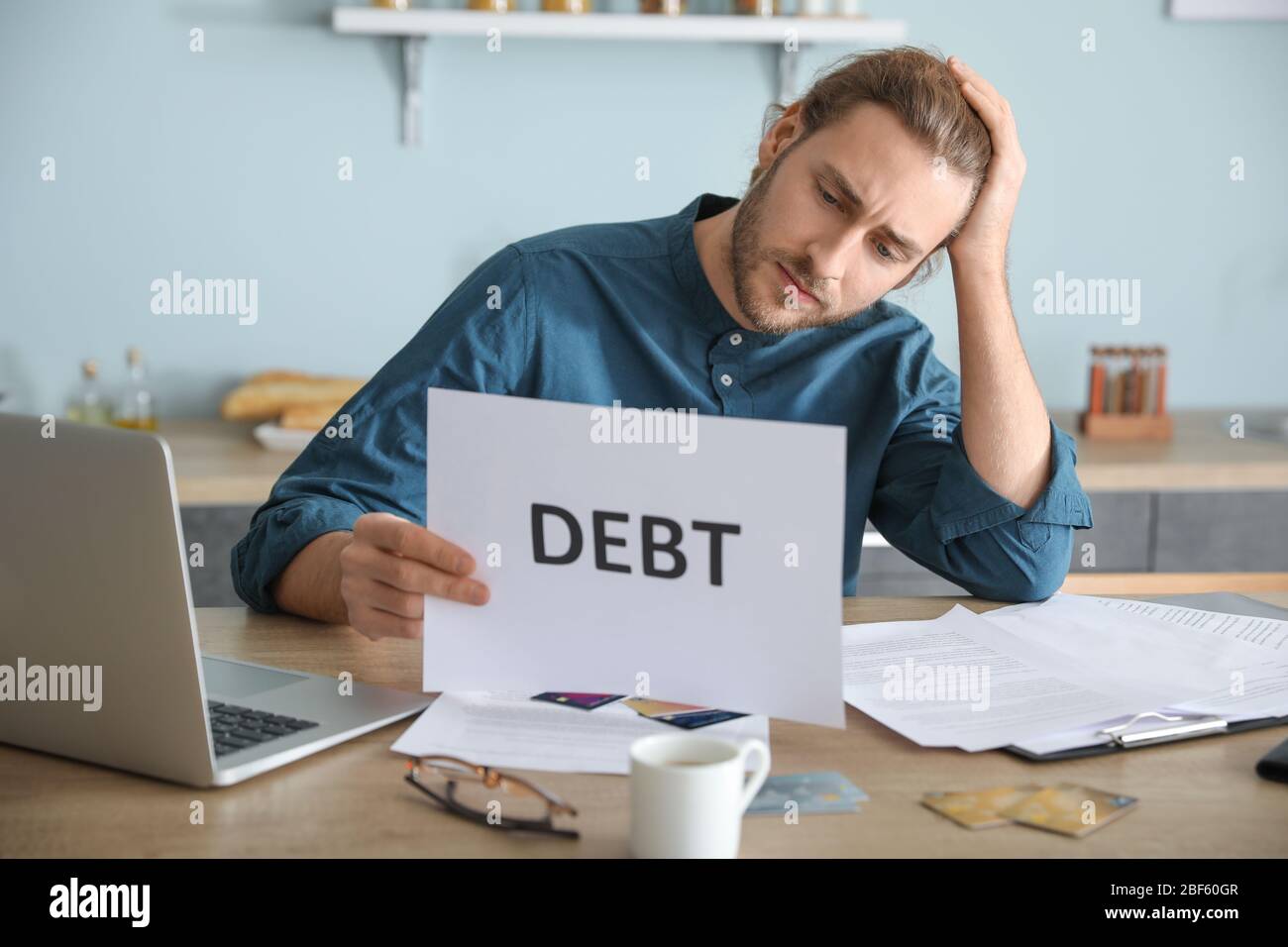 Worried young man in debt at home Stock Photo