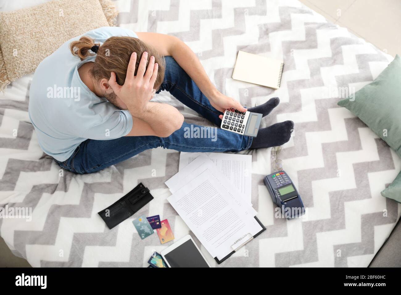 Worried young man in debt at home, top view Stock Photo - Alamy