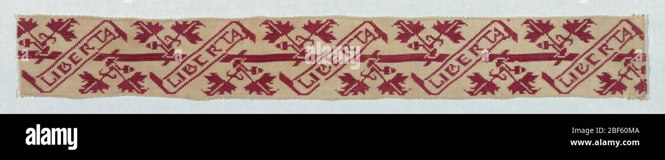 Band. Cream-colored band embroidered in red with the motto 'Liberta' contained in a diagonal-shaped scroll. Stylized leaves and acorns appear in between scrolls.. Stock Photo