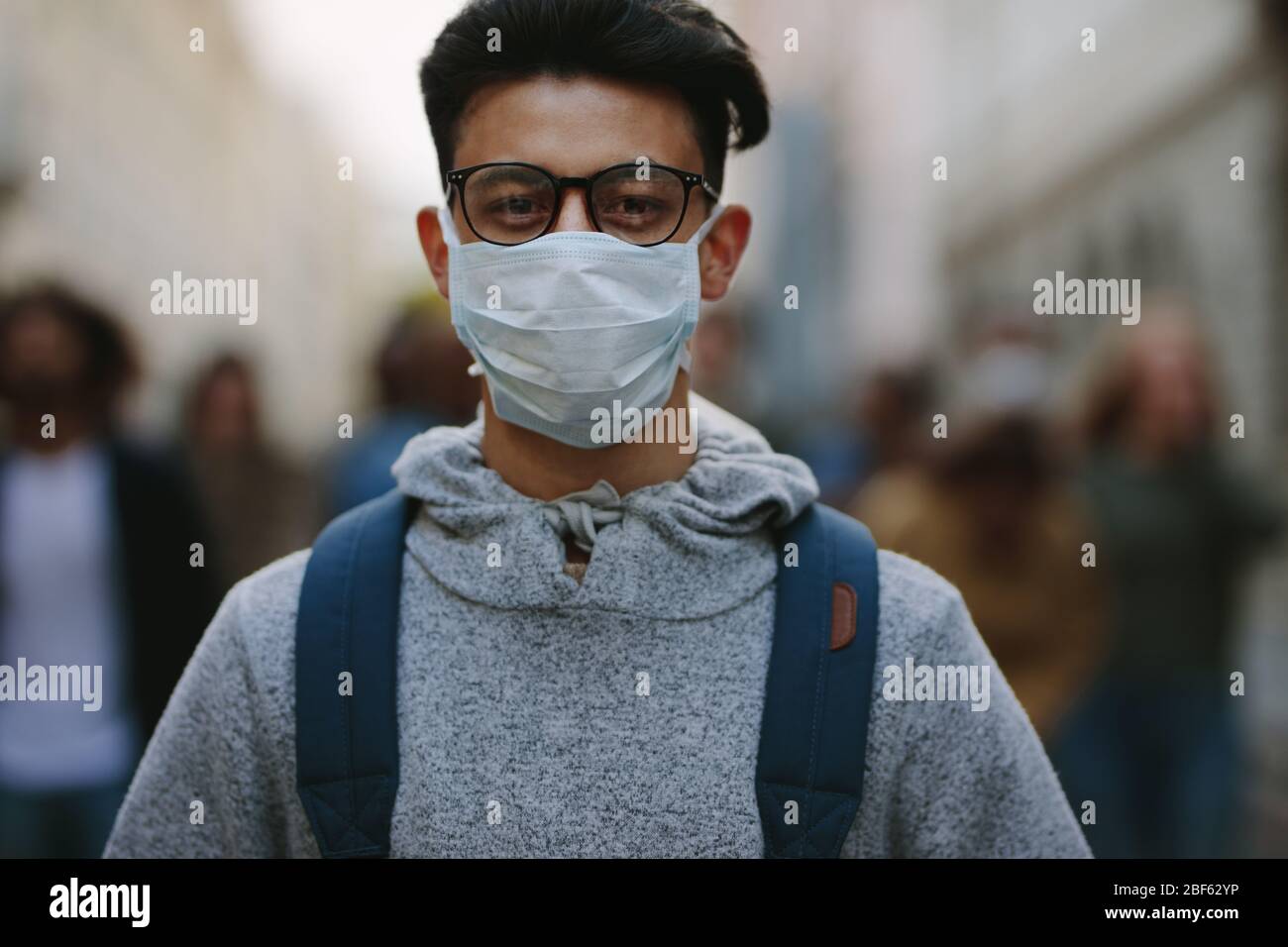 Young man wearing a face mask participate in a protest with group of demonstrator in background. Man protesting with group of rebellions outdoors on r Stock Photo