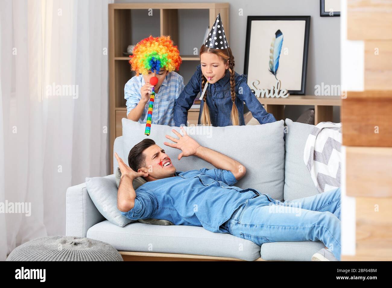 Children playing a prank on their father at home. April Fools' Day celebration Stock Photo