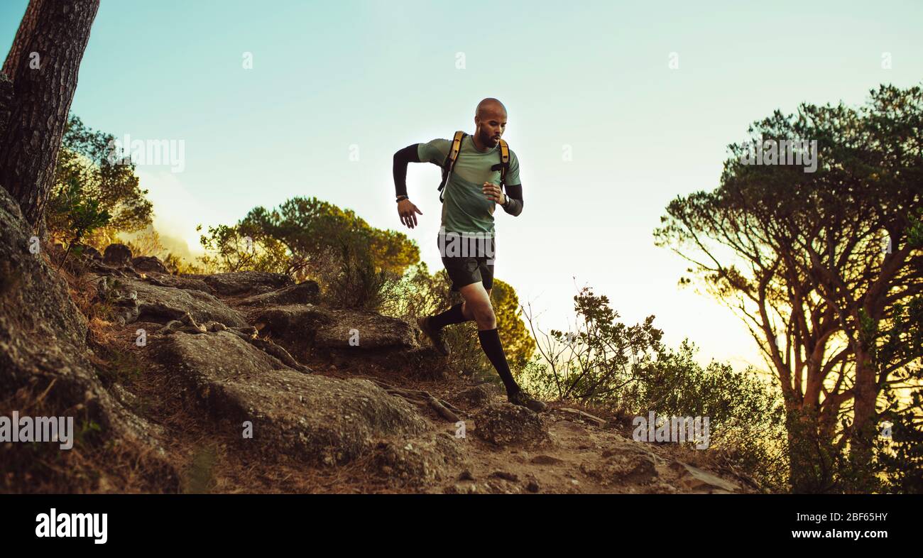 Man running on mountain trail. fitness male running through rocky mountain path. Stock Photo