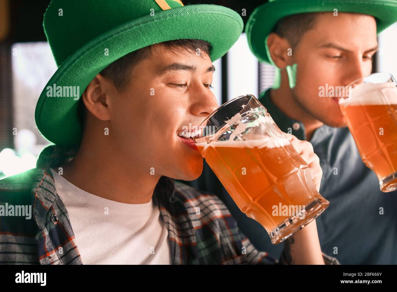 Young Asian man celebrating St. Patrick's Day in pub Stock Photo