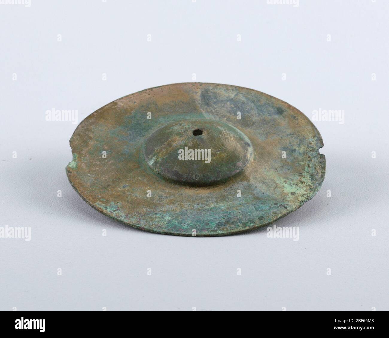 Cymbals. Circular form with raised dome, small hole in center. Green patina. Stock Photo