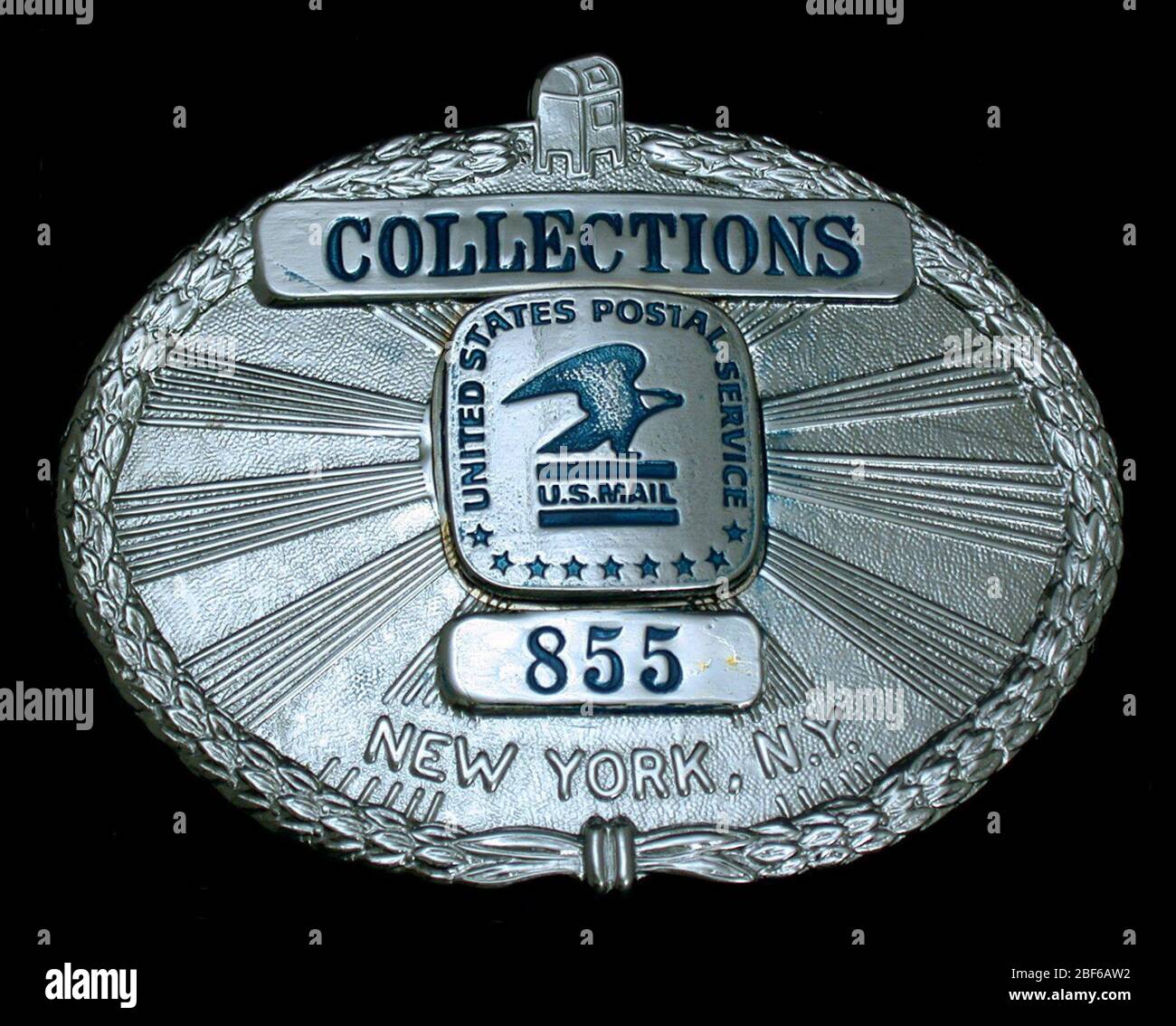 Collections Service Employee Chest Badge Number 855. United States Post Office Department Collections Service badge, number 855, with eagle emblem in center emanating rays; laurel wreath around the perimeter with street letterbox on top center. Stock Photo