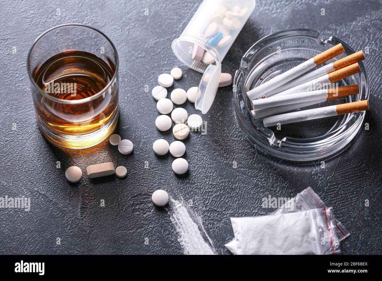 cigarettes and whisky Glass of whiskey with cigarettes and drugs on dark background Stock Photo