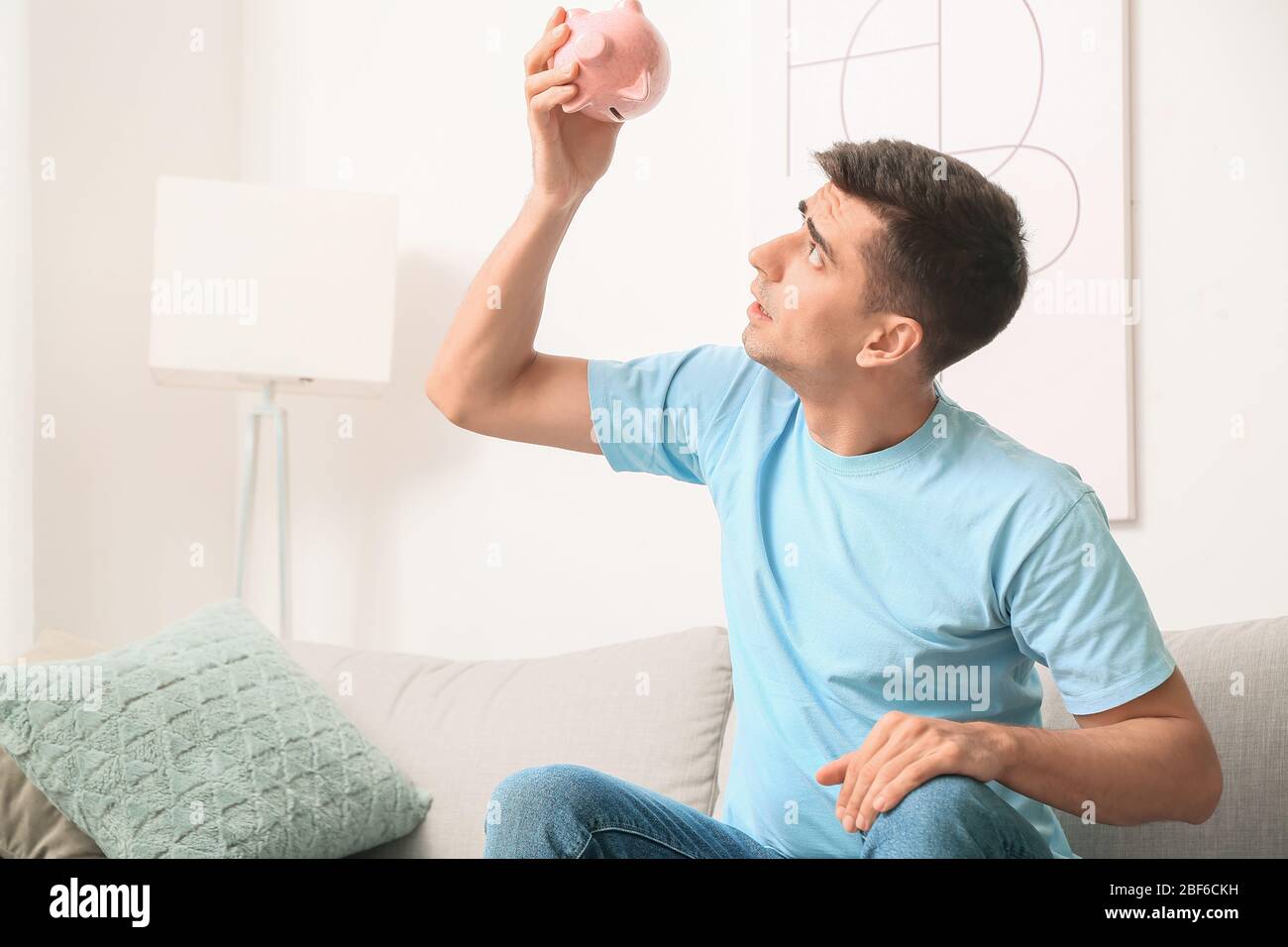 Worried man with empty piggy bank at home Stock Photo - Alamy