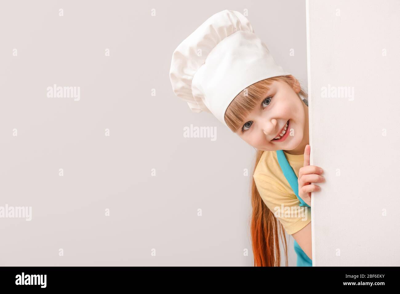 Cute little chef with blank poster on light background Stock Photo - Alamy