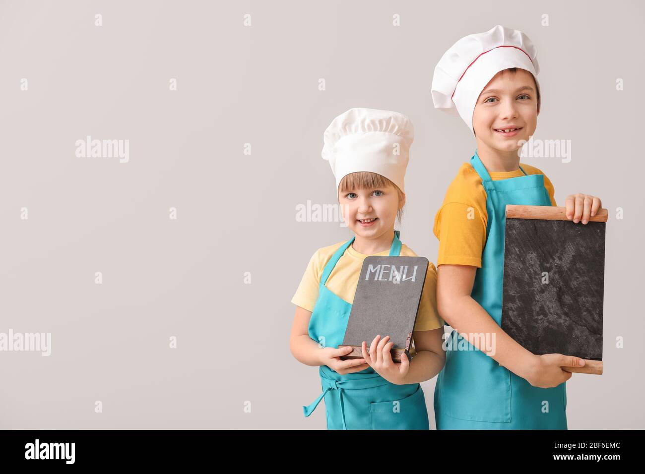 Cute little chefs with menu on light background Stock Photo - Alamy