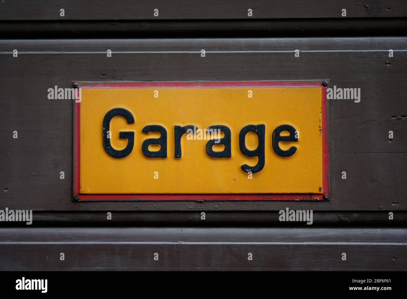 A garage sign, yellow with black letters and a red border. Södermalm, Stockholm. Stock Photo