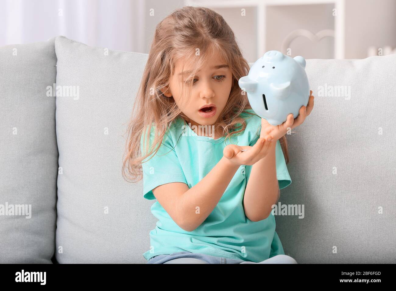 Worried cute girl with empty piggy bank at home Stock Photo - Alamy