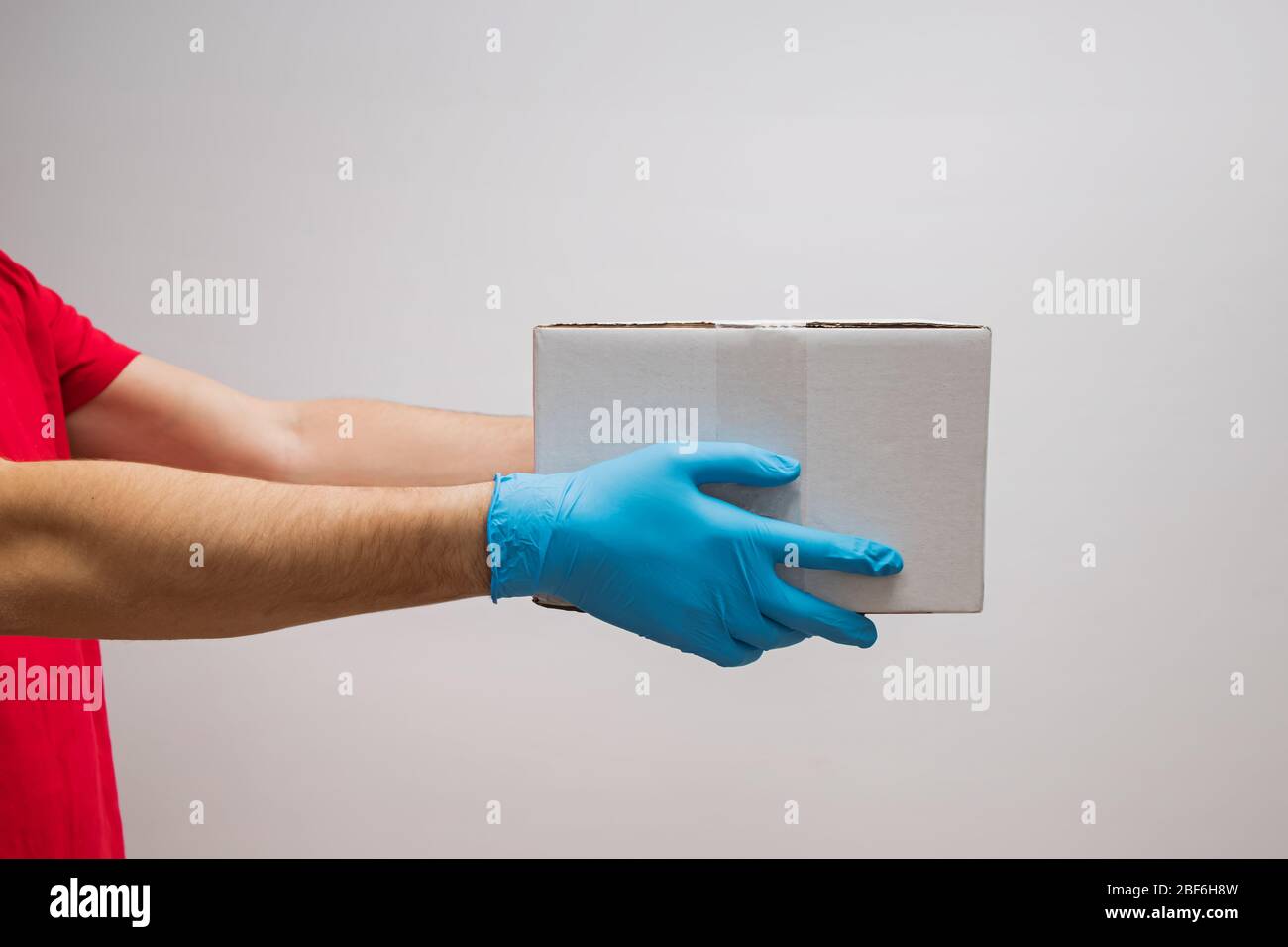 Delivery man holding cardboard boxes in protective rubber gloves Stock