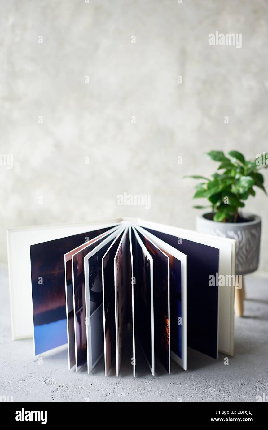 Photobook in hard leather cover on a gray concrete background. Making photos and storing them.A wedding album or book in an expensive binding. Stock Photo