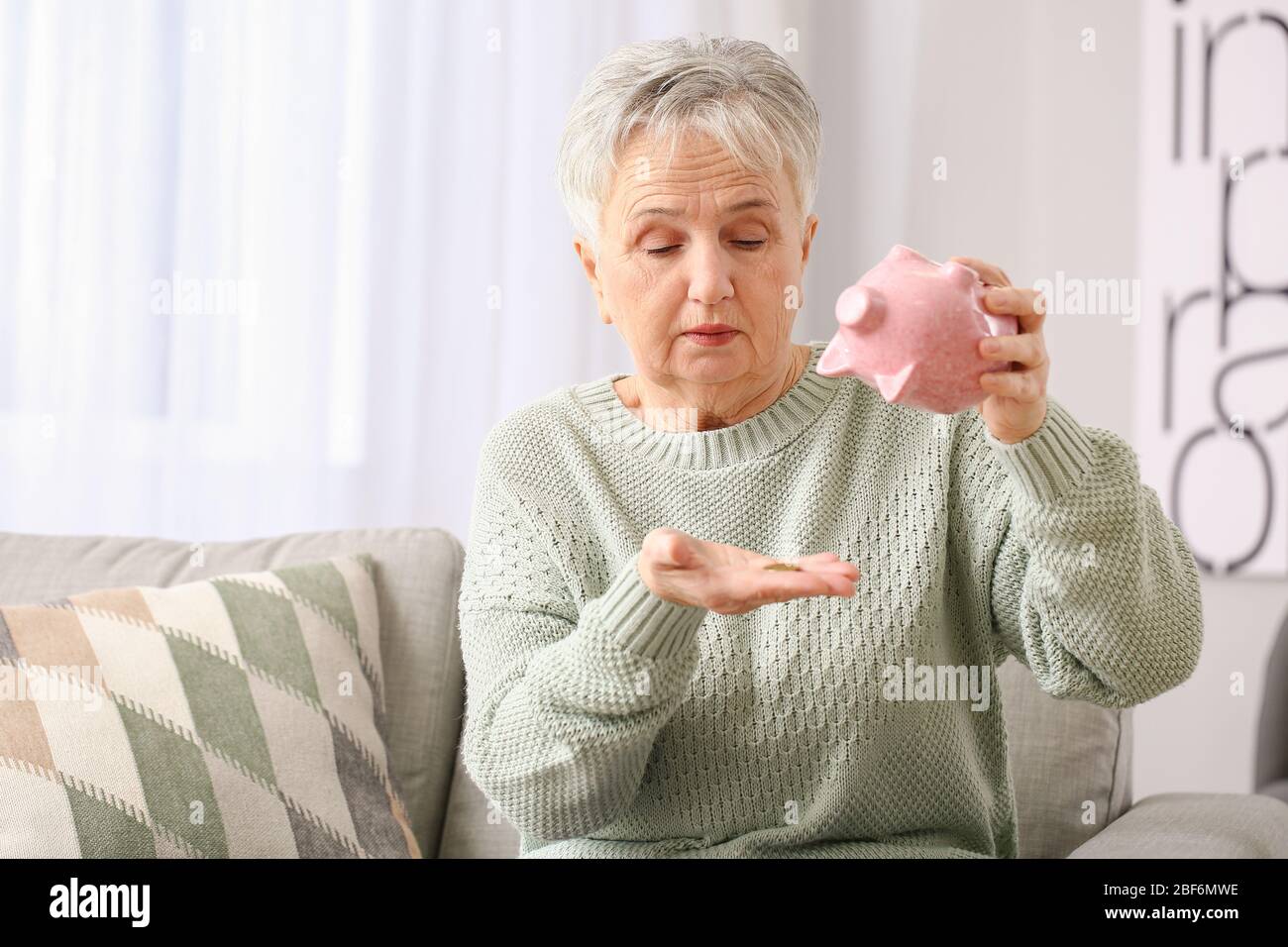 Sad senior woman with empty piggy bank at home Stock Photo - Alamy