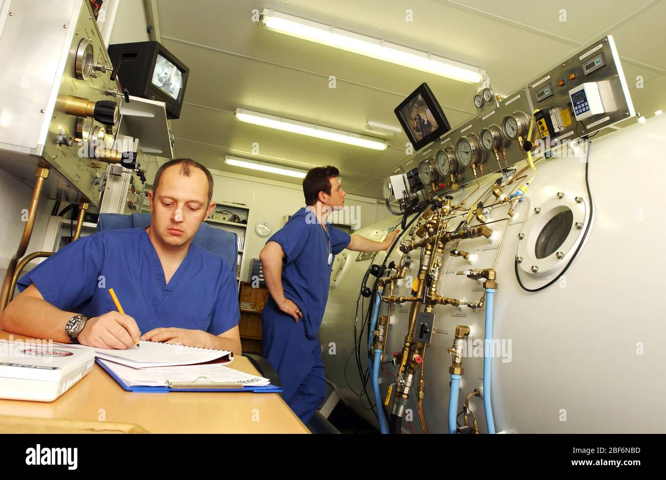 A hyperbaric technologist monitors a patient in the chamber, through a monitor as there are various cameras within the chamber. The technologist will Stock Photo
