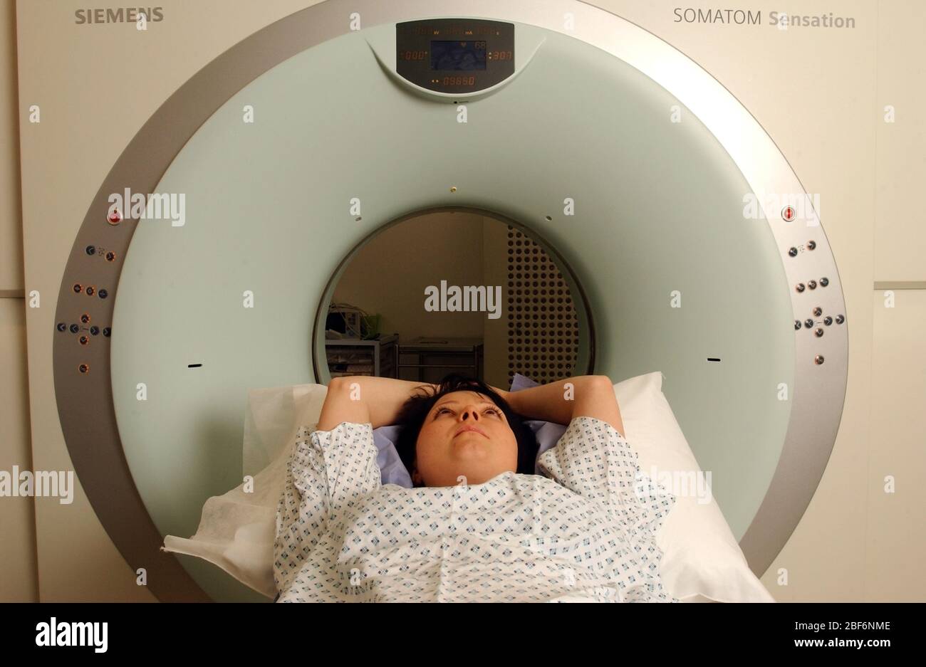 A Siemens CT scanner A patient lies on the examination table of a computed tomography scanner, better known as CAT or CT scanner, which produces three Stock Photo