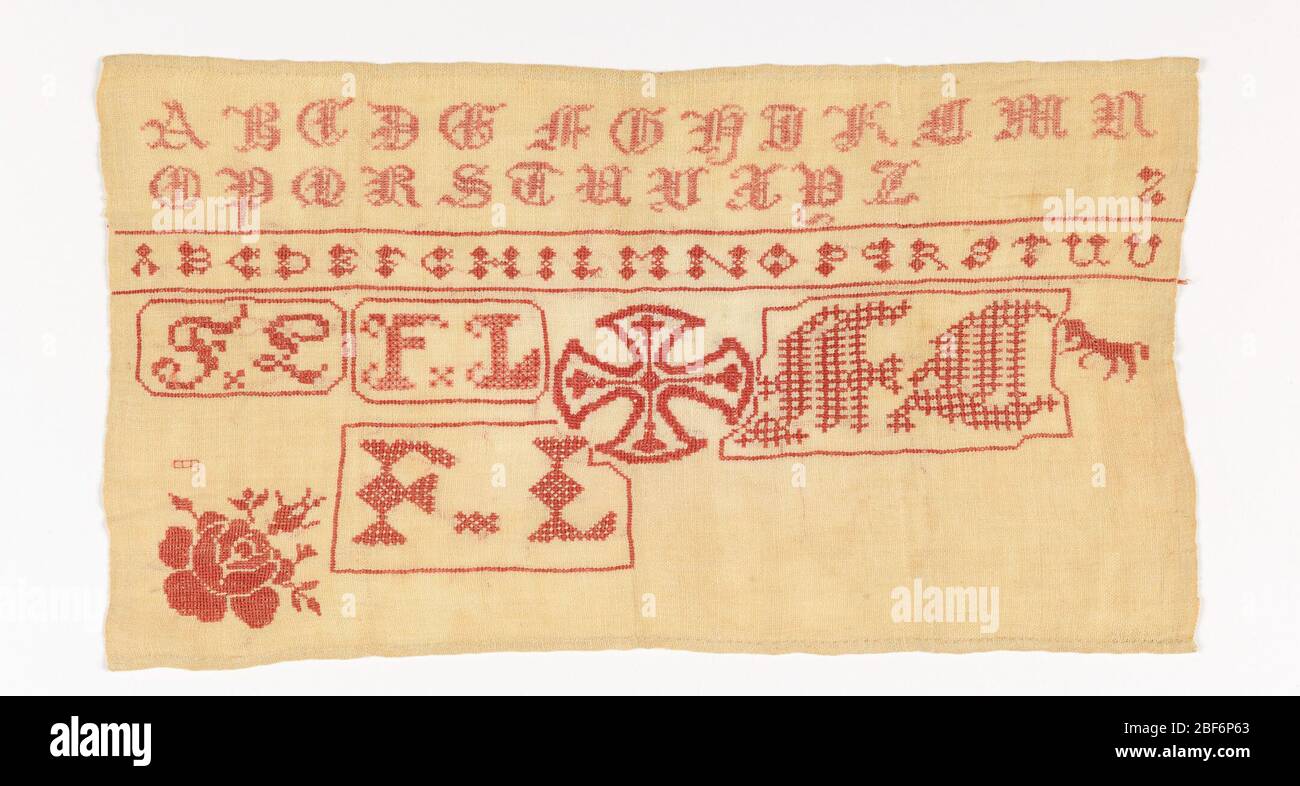 Sampler. Gothic alphabet, Maltese cross, and the initials FL embroidered in red on a white ground. Stock Photo