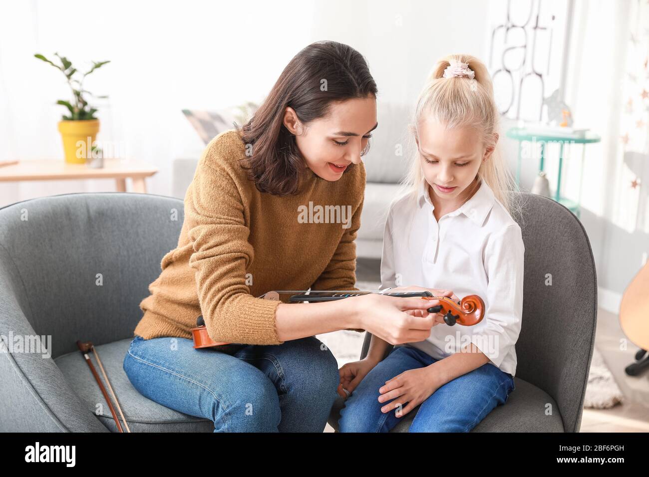 Private music teacher giving violin lessons to little girl at home ...