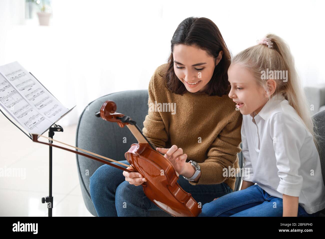 Private music teacher giving violin lessons to little girl at home ...