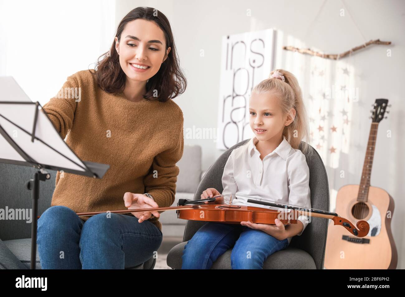 Private music teacher giving violin lessons to little girl at home ...