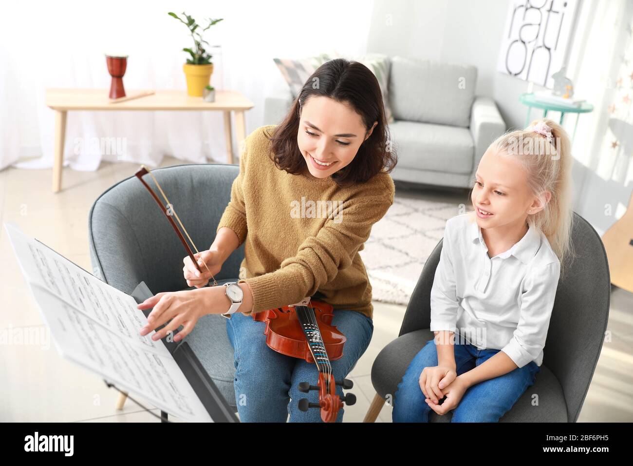 Private music teacher giving violin lessons to little girl at home ...