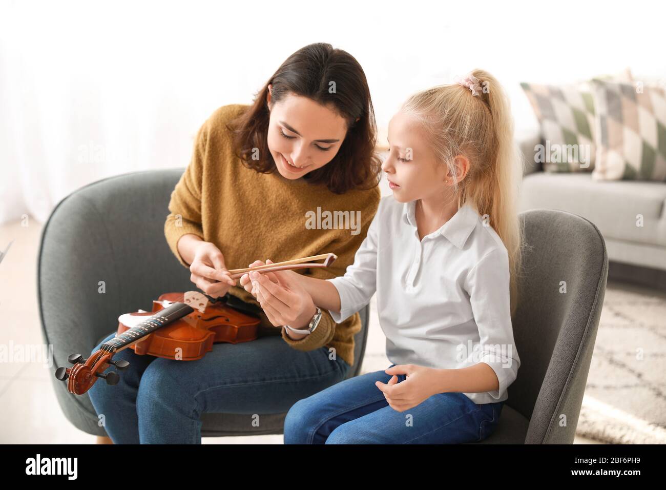 Private music teacher giving violin lessons to little girl at home ...
