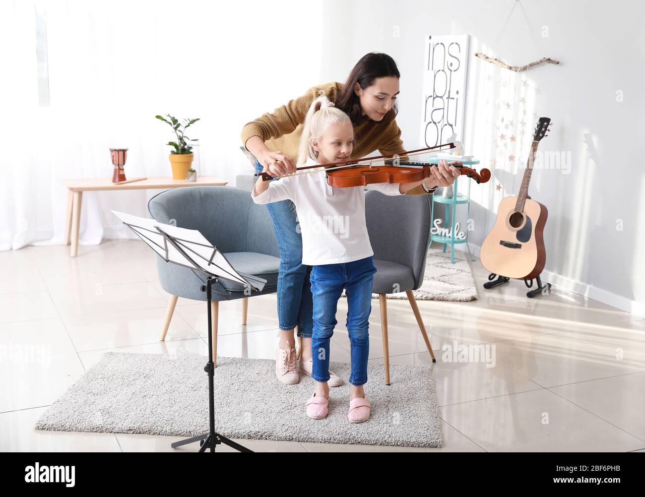 Private music teacher giving violin lessons to little girl at home ...