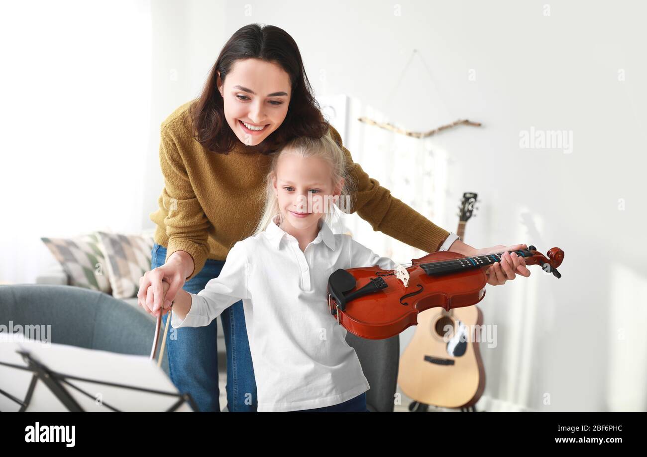 Private music teacher giving violin lessons to little girl at home ...