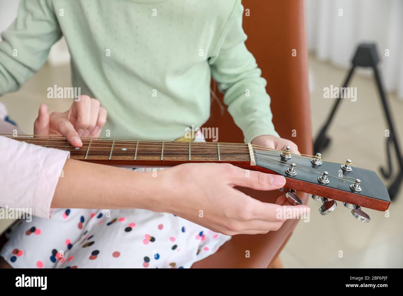 Private music teacher giving guitar lessons to little girl at home ...