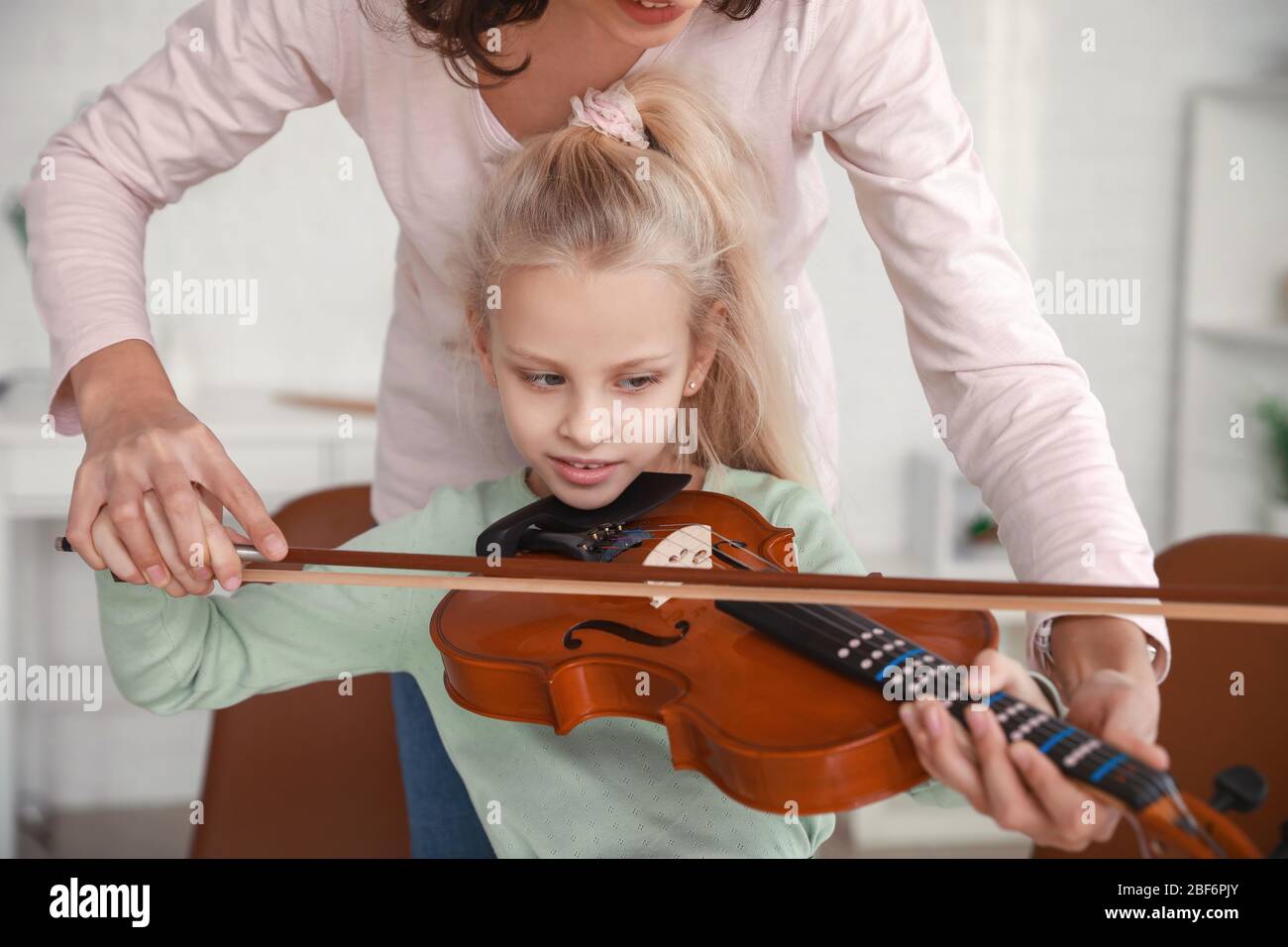 Private music teacher giving violin lessons to little girl at home ...
