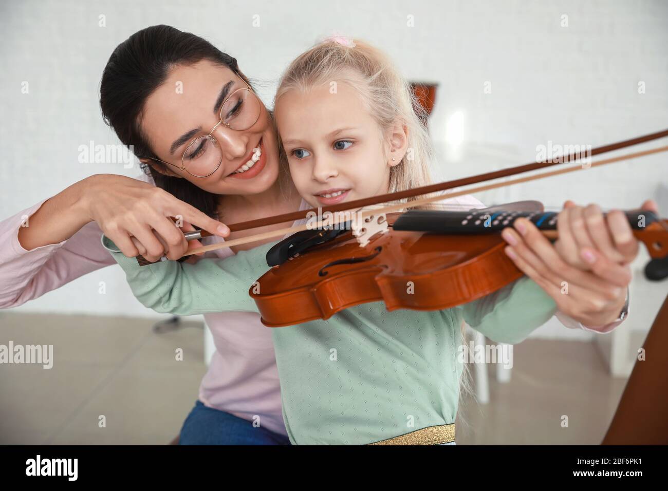 Private music teacher giving violin lessons to little girl at home ...