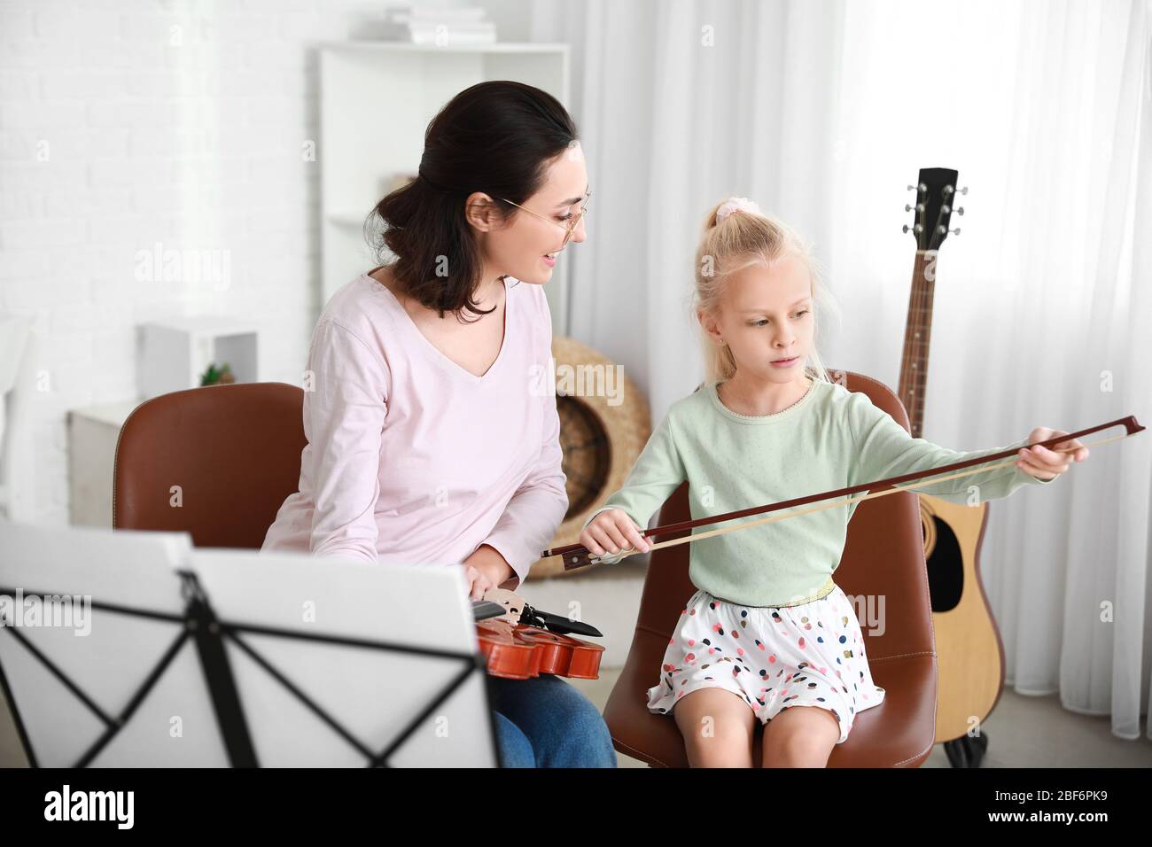 Private music teacher giving violin lessons to little girl at home ...