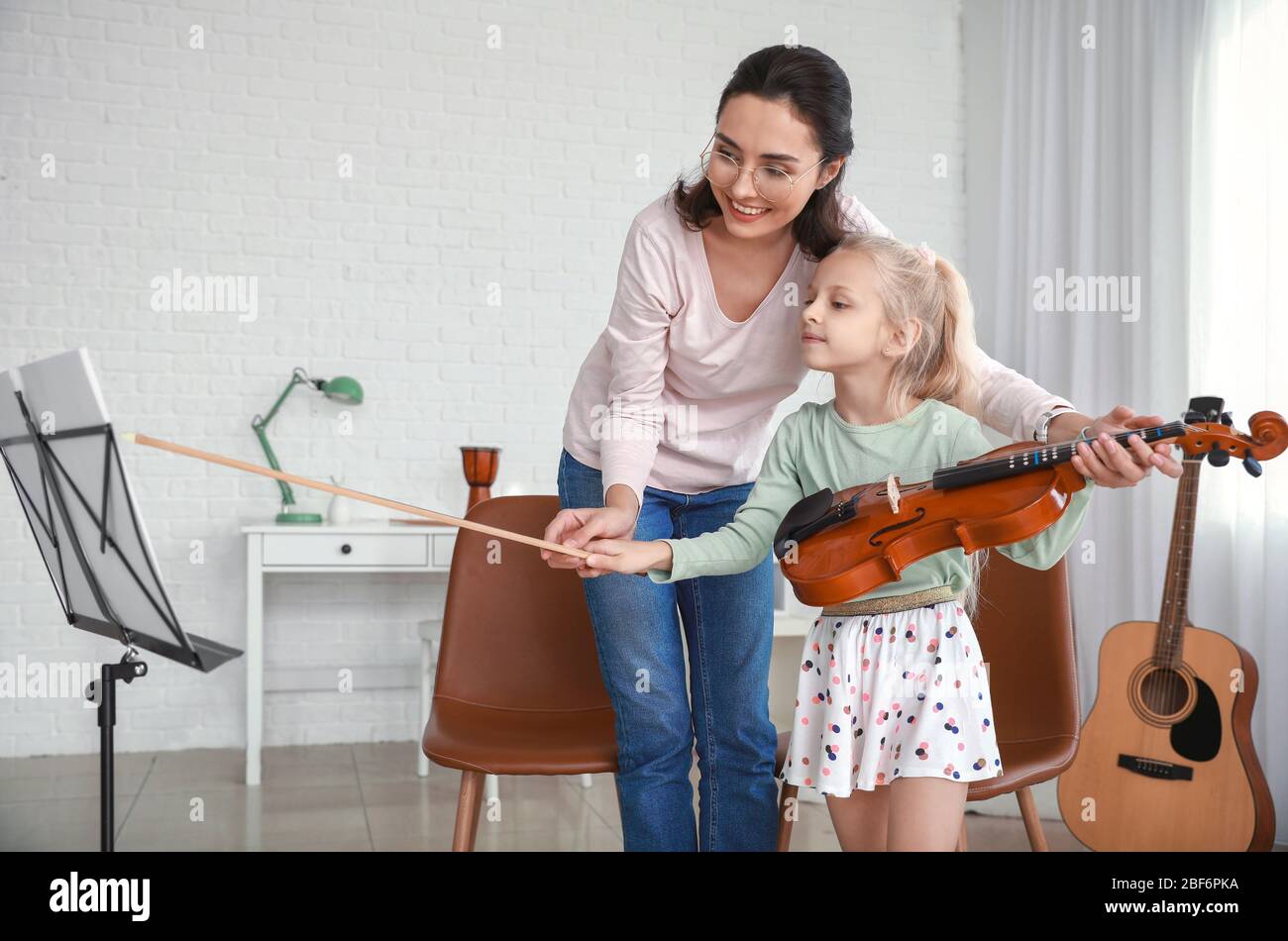 Private music teacher giving violin lessons to little girl at home ...