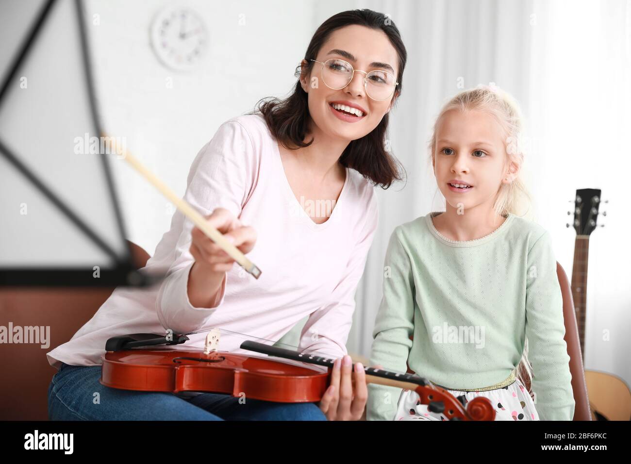 Private music teacher giving violin lessons to little girl at home ...